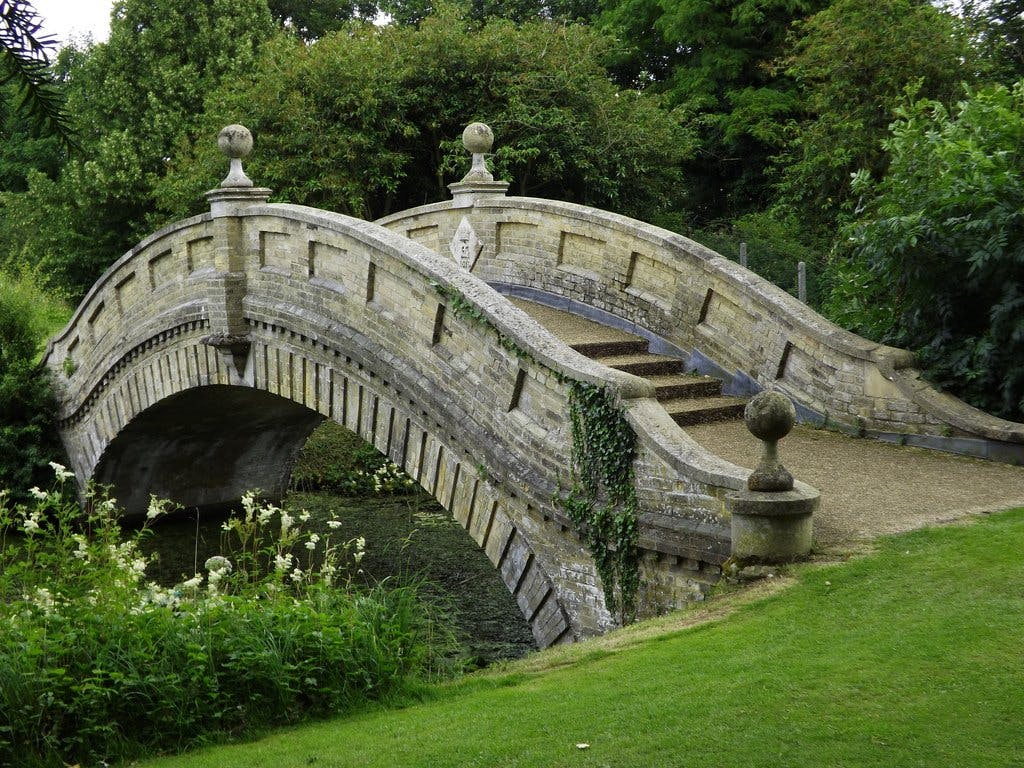 <p>The Chinese Bridge in Wrest Park is a historic stone footbridge that crosses the north end of Broad Water, a large lake in the park. The bridge was built in 1876 by the Countess Cowper, who was interested in Chinese culture and art. </p><p><br></p><p>The bridge, along with the nearby Chinese Temple, was inspired by the scenes found on Chinese willow pattern plates, which were popular in England at the time. The bridge is a unique architectural design that displays a good level of craftsmanship and detailing. It is listed as a Grade II building by Historic England, which means it is of special interest and worthy of preservation. </p><p><br></p><p>The bridge is part of the Wrest Park estate, which covers over 90 hectares of gardens and parkland. The park also features a baroque pavilion, a French-style mansion, and various statues and monuments. The park is open to the public and managed by English Heritage.</p>