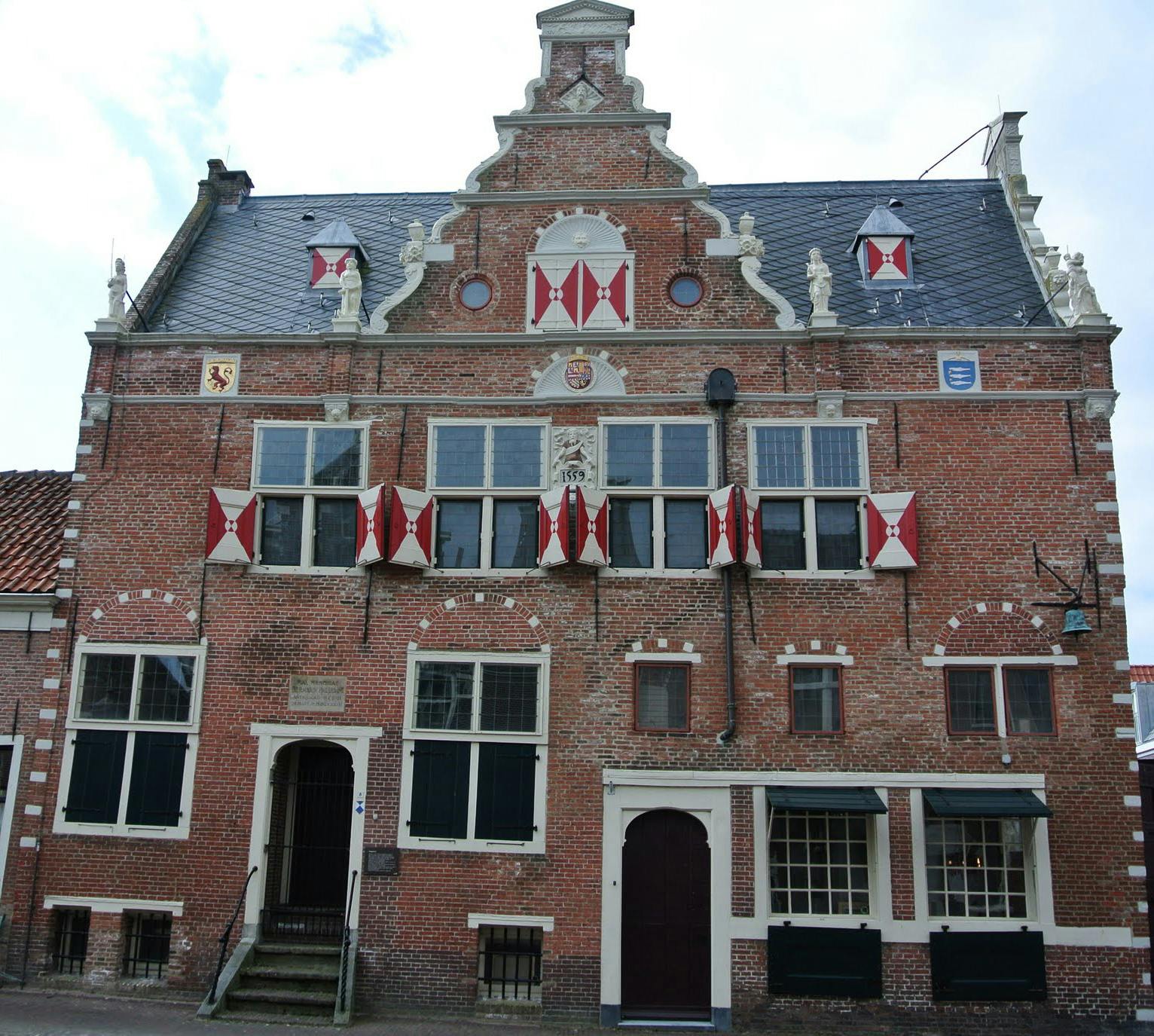 <p>The weighing house of Enkhuizen is a historic building that dates back to 1559. It was used to weigh goods that were traded in the city, such as cheese, butter, fish, and salt. The weighing house was also a symbol of the economic prosperity and civic pride of Enkhuizen, which was one of the most important ports of the Dutch Republic in the 17th century.</p><p><br></p><p>The weighing house is a fine example of the early Renaissance style in the northern Netherlands. It has a stepped gable, a clock tower, and a richly decorated façade with sculptures and coats of arms. The interior of the weighing house has been preserved, including the original weighing mechanism and scales.</p><p><br></p><p>On the first floor of the weighing house, there was a surgeon’s room, where the surgeon’s guild of Enkhuizen held meetings and lectures. The stained glass windows of this room bear the names of the surgeons and doctors who worked in Enkhuizen between 1639 and 1654. The surgeon’s room also contains a collection of medical instruments and anatomical models from the 17th and 18th centuries.</p><p><br></p><p>The weighing house of Enkhuizen is now a museum that showcases the history and culture of the city. It is part of the Zuiderzee Museum, which also includes an open-air museum with historical buildings from the region. The weighing house is open to visitors from April to October, from 10:00 to 17:00.</p><p><br></p><p><u>Some additional information or questions that you might find interesting are</u></p><p><br></p><p>Enkhuizen was one of the founding cities of the Dutch East India Company (VOC), which was the first multinational corporation and the largest trading company in the world. The weighing house of Enkhuizen was also used to weigh the spices and other exotic goods that the VOC brought back from Asia.</p><p><br></p><p>The weighing house of Enkhuizen has a special connection to the famous Dutch painter Rembrandt van Rijn. In 1636, he painted a portrait of the surgeon Nicolaes Tulp, who was a member of the surgeon’s guild of Enkhuizen and had his name on one of the stained glass windows of the weighing house. The portrait, known as The Anatomy Lesson of Dr. Nicolaes Tulp, is one of Rembrandt’s most famous works and shows Tulp dissecting a corpse in front of his students.</p>