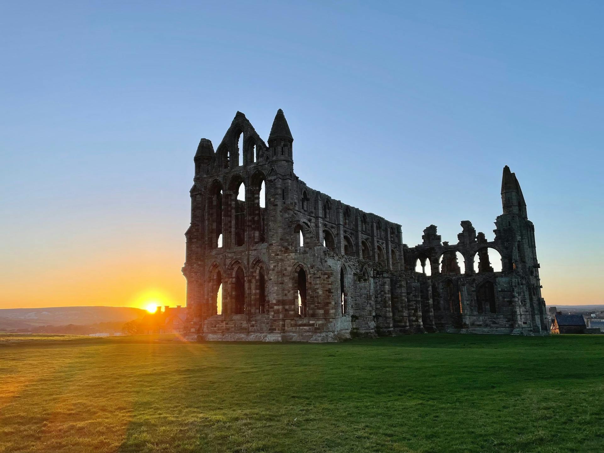 <p>Whitby Abbey and Dracula have a fascinating relationship that spans over a century. Here is some extensive information on how the abbey inspired Bram Stoker to write his famous novel, and how the novel influenced the abbey and the town of Whitby.</p><p><br></p><p><strong>Bram Stoker’s visit to Whitby</strong></p><p>Bram Stoker, an Irish writer and theatre manager, visited Whitby in July 1890, looking for a quiet place to relax and work on his new story. He stayed at a guesthouse on Royal Crescent, where he had a view of the abbey and the church on the cliff. He was captivated by the Gothic atmosphere of the town, and explored its history, legends, and folklore.</p><p><br></p><p>He also visited the public library, where he found a book called An Account of the Principalities of Wallachia and Moldavia, which introduced him to the name and deeds of Vlad the Impaler, a 15th-century prince of Wallachia who was notorious for his cruelty and bloodthirstiness. Stoker decided to use Vlad’s surname, Dracula, which means <em>son of the dragon</em> or <em>son of the devil</em>, for his main character, who was originally called Count Wampyr.</p><p><br></p><p><strong>Dracula’s arrival in Whitby</strong></p><p>Stoker incorporated many elements of Whitby into his novel, which was published in 1897. The most dramatic scene is when Dracula arrives in Whitby on a Russian ship called the Demeter, which is carrying 50 boxes of earth from Transylvania. The ship is caught in a storm and runs aground on Tate Hill Sands, near the harbour.</p><p><br></p><p>The only survivor is the captain, who is found tied to the wheel with a crucifix in his hand. A large black dog, which is Dracula in disguise, leaps from the ship and runs up the 199 steps to the abbey. He then finds a lair in the ruins, where he hides some of his coffins.</p><p><br></p><p><strong>Dracula’s victims in Whitby</strong></p><p>Dracula begins to prey on the people of Whitby, starting with a local old man named Swales, whose name Stoker borrowed from a gravestone in the churchyard. He then targets Lucy Westenra, a young woman who is staying with her friend Mina Murray at a house on the Crescent. Lucy sleepwalks at night and wanders to the churchyard, where Dracula bites her and drains her blood.</p><p><br></p><p>Mina notices Lucy’s pale and weak condition, and also sees a strange red mark on her neck. Lucy eventually dies and becomes a vampire herself, but is later destroyed by Van Helsing and his companions. Mina is also attacked by Dracula, who forces her to drink his blood and creates a psychic bond between them. This bond allows Mina to track Dracula’s movements, and helps the heroes to pursue him back to Transylvania, where they finally kill him.</p><p><br></p><p><strong>Dracula’s legacy in Whitby</strong></p><p>Dracula is one of the most influential and popular novels in the history of literature, and has spawned countless adaptations, sequels, and spin-offs. Whitby has also benefited from its association with Dracula, as it attracts many tourists and fans who want to see the places that inspired Stoker. The abbey, the church, the steps, the harbour, and the museum are some of the main attractions for Dracula enthusiasts.</p><p><br></p><p>Whitby also hosts various events and festivals related to Dracula, such as the Whitby Goth Weekend, the Bram Stoker Film Festival, and the Dracula Experience. Whitby Abbey itself celebrates its connection to Dracula by projecting images of bats on its walls, and by hosting a world record attempt for the largest gathering of people dressed as vampires.</p><p><br></p>