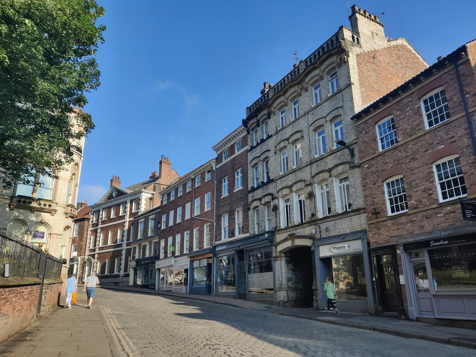 <p>Micklegate is a historic street in the city of York, England. It means <em>Great Street</em> in Old Norse, and was the main entrance to the city from the south.</p><p><br></p><p><u>Micklegate has been the site of many important events and buildings, such as</u></p><p><br></p><p>Micklegate Bar, the most important of York’s four medieval gateways, and the focus for grand events. It was the royal entrance to the city, and the place where the severed heads of rebels and traitors were displayed. The lower section of the bar dates from the 12th century, and the top two storeys from the 14th.</p><p><br></p><p>Holy Trinity Church, a parish church of the Church of England, dating from the 12th century. It has a Norman nave, a 15th-century tower, and a 17th-century chancel. It also contains some medieval stained glass and monuments.</p><p><br></p><p>The Priory of the Holy Trinity, a Benedictine monastery founded in the 11th century, and dissolved in the 16th century. It was located on the south side of Micklegate, and its remains can still be seen in Priory Street.</p><p><br></p><p>The Bar Convent, the oldest surviving Roman Catholic convent in England, founded in 1686. It is now a museum, a guest house, and a conference centre. It has a 19th-century Gothic chapel, a library, and a collection of religious artefacts.</p><p><br></p><p>The Micklegate Run, a traditional soapbox race held every August bank holiday since 1964. It involves teams of amateur racers competing in homemade carts down the steep slope of Micklegate. It attracts thousands of spectators and raises money for charity.</p><p><br></p><p>Micklegate is also known for its Georgian architecture, its views of the river Ouse, and its lively nightlife. It has many pubs, restaurants, and clubs, and is popular with locals and tourists alike</p><p>Micklegate is one of the most handsome and rewarding streets in York, and has a rich and varied history.</p>