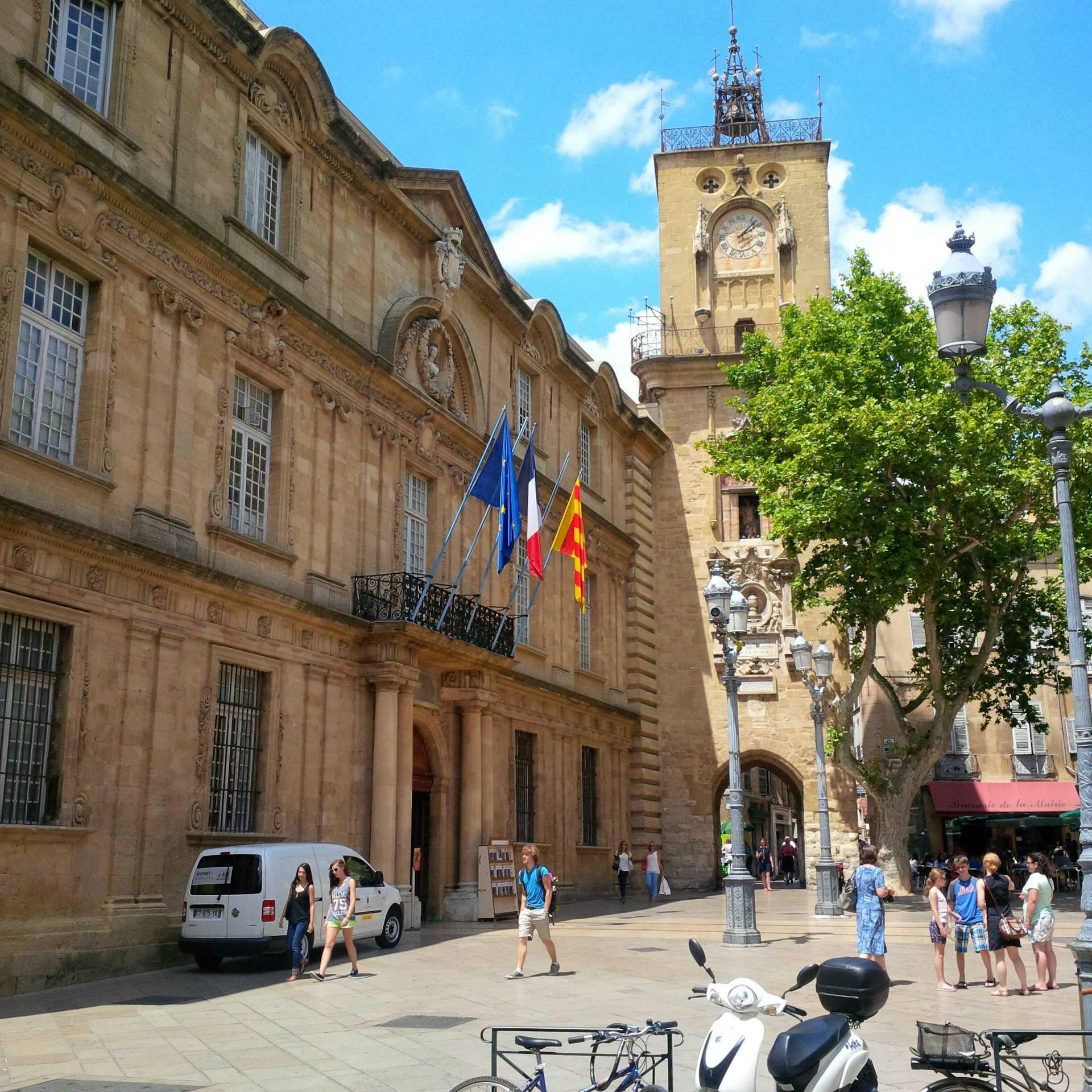 <p>Aix-en-Provence City Hall, also known as Hôtel de Ville, is a historic building located in the heart of the city. It was built in the 17th century, and has a rich architectural and artistic heritage. </p><p><br></p><p><u>Here are some of the main features of the City Hall:</u></p><p><br></p><p>The façade, inspired by Italian palaces, was designed by Pierre Pavillon, a local architect, with the assistance of the sculptors Jean-Claude Rambot and Jean-Baptiste Fossé. The façade has statues of angels, and busts of counts of Provence and King Louis XIV, although some of them were damaged or destroyed during the French Revolution.</p><p><br></p><p>The entrance is framed by two double Doric columns linked by an entablature which support a fine wrought-iron balcony dating from 1661. Each leaf of the wooden door is decorated with a lion’s head knocker designed by Pierre Pavillon. This door leads to the square inner courtyard, where there is a fountain and a porch supporting a state balcony.</p><p><br></p><p>The twin winding staircases lead to the magnificent Salle des Etats de Provence (House of Representatives), where the provincial parliament used to meet. The original decoration of the hall, dating from the 18th century, was destroyed in 17921. The present paintings illustrating the history of the city and of Provence were done between 1899 and 1905 by Henri Martin, Paul Gervais, and Edouard Detaille.</p><p><br></p><p>The City Hall also houses the Musée du Vieil Aix (Museum of Old Aix), which displays collections of furniture, ceramics, costumes, and paintings related to the history and culture of Aix-en-Provence.</p><p><br></p>