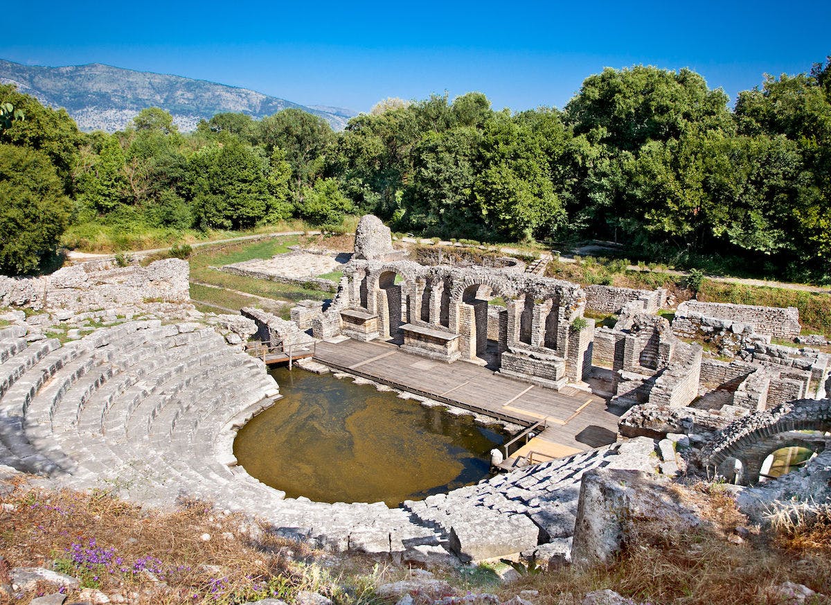 <p>Butrint is a historic and archaeological site in southern Albania, near the border with Greece. It has been inhabited since prehistoric times and has witnessed the rise and fall of various civilizations, such as the Greeks, Romans, Byzantines, Venetians, and Ottomans. It is a UNESCO World Heritage Site and a National Park, and it offers a rich cultural and natural heritage to visitors. </p><p><br></p><p><u>Here are some of the main features of Butrint</u></p><p><br></p><p><strong>The fortifications</strong></p><p>Butrint has a complex system of defensive walls and towers that span different periods of history, from the ancient Greek colony to the 19th century fortress of Ali Pasha. The fortifications reflect the strategic importance of Butrint as a port and a crossroads of cultures.</p><p><br></p><p><strong>The theatre</strong></p><p>The ancient Greek theatre of Butrint is one of the best preserved monuments in the site. It was built in the 4th century BC and could seat up to 1500 spectators. It was used for theatrical performances, religious ceremonies, and political assemblies. The theatre was later modified by the Romans and the Byzantines, who added a stage and a baptistery.</p><p><br></p><p><strong>The baptistery</strong></p><p>The baptistery is a remarkable example of early Christian architecture and art. It was built in the 6th century AD on the site of a Roman monument. It has a circular plan with a central pool and eight surrounding niches. The floor is decorated with a mosaic of geometric and floral patterns, as well as scenes from the Bible and the life of Christ. The baptistery was part of a larger complex that included a basilica, a baptistery, and a bishop’s palace.</p><p><br></p><p><strong>The basilica</strong></p><p>The basilica was the main church of Butrint and the seat of the bishop. It was built in the 5th century AD and rebuilt in the 9th century AD. It has a typical plan of three naves, a transept, and an apse. The walls are decorated with frescoes and marble columns. The basilica was damaged by an earthquake in the 10th century AD and abandoned in the Middle Ages.</p><p><br></p><p><strong>The museum</strong></p><p>The museum of Butrint is located in the castle of Ali Pasha, a 19th century Ottoman ruler who controlled the region. The museum displays a collection of artifacts and sculptures from the site, dating from the prehistoric to the medieval periods. The museum also offers a panoramic view of the lagoon and the surrounding landscape.</p><p><br></p><p>Butrint is a fascinating place to explore and learn about the history and culture of the Mediterranean. It is also a beautiful natural setting, with a lagoon, a wetland, a forest, and a variety of flora and fauna. Butrint is a treasure of Albania and a must-see for anyone interested in archaeology and nature.</p>